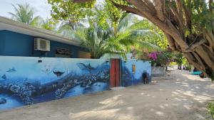 una parete blu con un dipinto di pesce sopra di Bird Beak Beach a Omadhoo