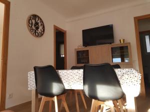 einem Esstisch mit vier Stühlen und einer Uhr an der Wand in der Unterkunft Fantàstic Pis a Oliana Alt Urgell Lleida Wifi in Oliana