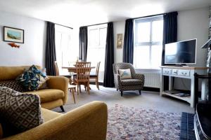 a living room with a couch and chairs and a television at Saffron House in Fowey