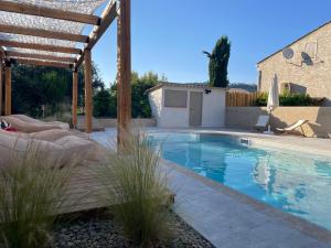 uma piscina num quintal com uma pérgula de madeira em Sous les étoiles en Provence, gîte les Grands chênes em Lurs