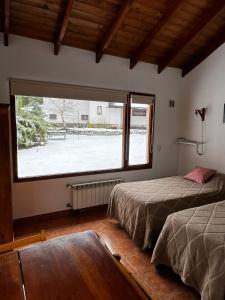 a bedroom with two beds and a large window at Schuss Cerro Catedral ARG41 in San Carlos de Bariloche