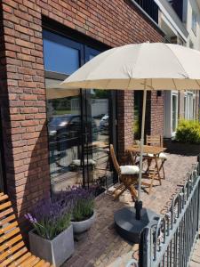 a patio with an umbrella and a table and chairs at Zilt aan Zee in Egmond aan Zee