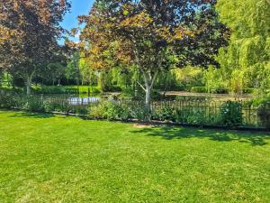 una valla en un parque con un árbol y un estanque en Rumbolds Retreat en Plaistow