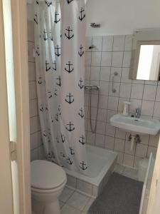 ein Badezimmer mit einem Duschvorhang, einem Waschbecken und einem WC in der Unterkunft Jegenye Vendégház in Balatonfüred