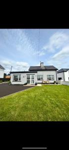 a large white house with a lawn in front of it at Eddies Lodge & Spa 3 bedroom cottage in Dungiven