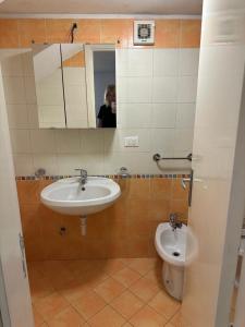 une personne prenant une photo d'une salle de bains avec lavabo et toilettes dans l'établissement Casetta Gabriella, à Ischia