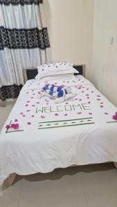białe łóżko z różowymi kwiatami w obiekcie Bird Beak Beach w mieście Omadhoo