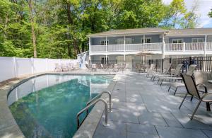 a swimming pool with chairs and a house at Studio East Motel in Ogunquit