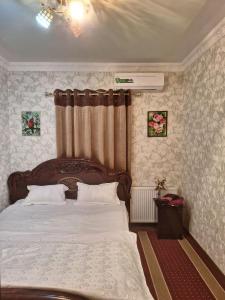 a bedroom with a large bed with a wooden headboard at B&B Giza Registan in Samarkand