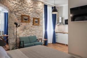 a bedroom with a blue chair and a stone wall at Photel studio Apartments in Crikvenica