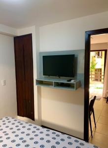 a bedroom with a flat screen tv on a wall at Solar pipa apartments in Pipa