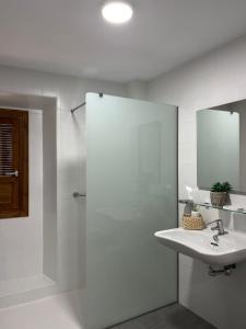 a bathroom with a sink and a shower with a mirror at Clarisas Suites in Carmona