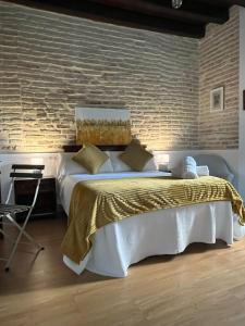 1 dormitorio con 1 cama grande y pared de ladrillo en Clarisas Suites en Carmona