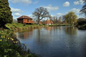 a wooden house next to a river with a building at SHEPHERDS HUT in Kent