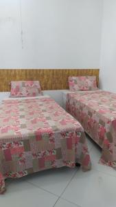 dos camas sentadas una al lado de la otra en una habitación en Pousada Oliveiras, en Tobias Barreto