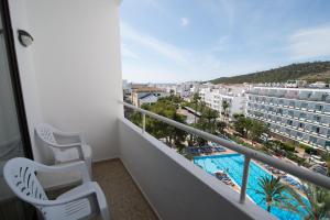einen Balkon mit 2 Stühlen und einem Pool in der Unterkunft Apartamentos Mestret in Sant Antoni de Portmany