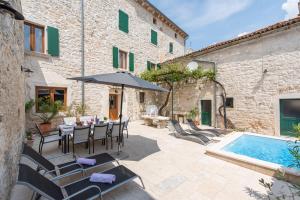 eine Terrasse mit einem Tisch, einem Sonnenschirm und einem Pool in der Unterkunft Villa San Vincenti in Svetvinčenat