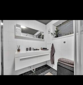 een witte badkamer met een wastafel en een raam bij Northern Light Tromsø in Tromsø