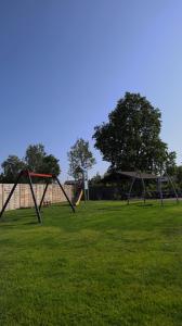 a park with two swings in the grass at Lazurowy Zakątek in Dąbki