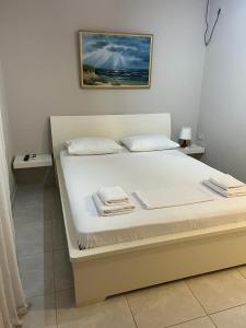 a white bed in a bedroom with a picture on the wall at Vila Mateo in Sarandë