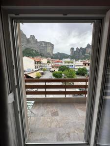 a window with a view of a city and mountains at Meteora Gold and Glass in Kalabaka