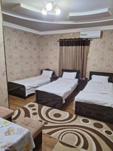 een kamer met drie bedden en een tapijt bij B&B Giza Registan in Samarkand
