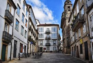 an alley with chairs and buildings in a city at GS Superb apartment with public garage in Santiago de Compostela