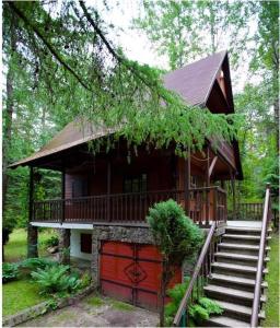 eine Blockhütte mit einer Treppe, die zu einem Haus führt in der Unterkunft Dowcień in Burdeniszki