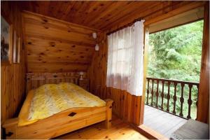 Łóżko w drewnianym pokoju z balkonem w obiekcie Dowcień w mieście Burdeniszki