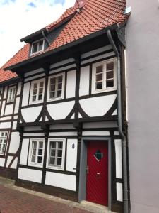um edifício preto e branco com uma porta vermelha em Charmantes Fachwerkhaus in der Innenstadt em Minden