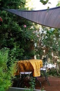 een tafel en stoelen met een gele deken erop bij Le Provencou in Tulette