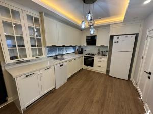 cocina con armarios blancos y nevera blanca en Özel Havuzlu Muhteşem Villa, en Aksu