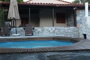 una piscina con terraza de madera y una casa en Μουριές, en Kamariótis