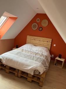 een bed in een slaapkamer met een oranje muur bij Gite Le Long de l'eau in Long