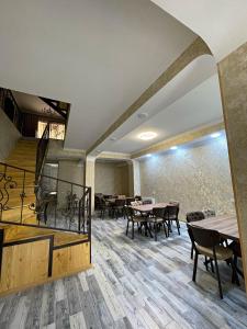 a dining room with tables and chairs and a staircase at Hotel Shina in Stepantsminda