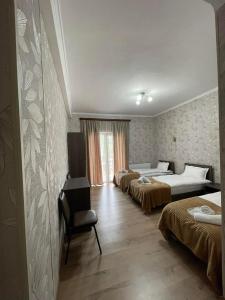 a hotel room with three beds and a chair at Hotel Shina in Kazbegi