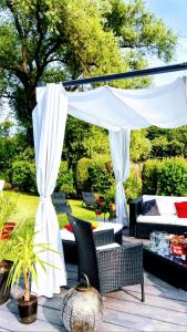 een patio met een witte luifel, stoelen en een tafel bij Gîte de la Vallée in Dambach
