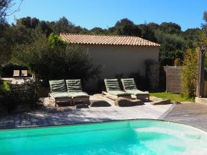 a swimming pool with two lounge chairs and a house at songes d été 6 in Bonifacio