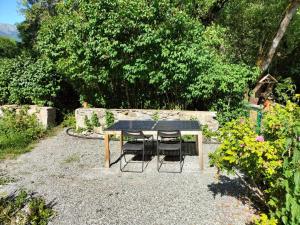 una mesa y dos sillas sentadas en un jardín en Appartement T2 40m2 avec extérieur 4 couchages, en Saint-Bonnet-en-Champsaur