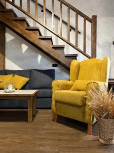 sala de estar con silla amarilla y sofá en La CasuKa VUT Fabero, en Fabero