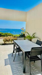 - une table et des chaises sur une terrasse avec vue sur l'océan dans l'établissement VUE MER IMPRENABLE ET PISCINE, à Bandol