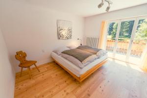 a bedroom with a bed and a chair and windows at Casa Nonna in Lenzerheide