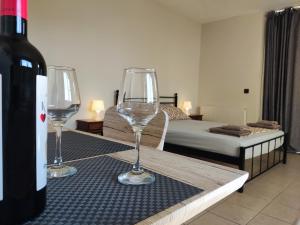 two wine glasses sitting on a table next to a bedroom at Yiorgos, amazing sunset view house in Psalidi