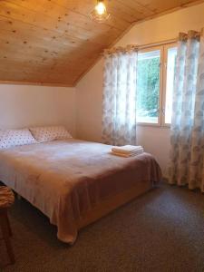 um quarto com uma cama grande e uma janela em Cosy wooden house in the heart of Apuseni. em Beliş