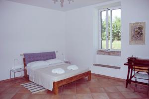 a white bedroom with a bed and a window at Agriturismo Morani in Santa Severa