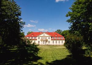 a large house with a red roof on a green field at Gutshaus Gevezin in Gevezin