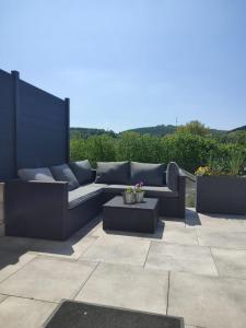 a patio with a couch and a table on a patio at La maison des Oiseaux in Martelange +9 photos