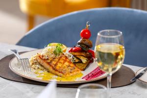 a plate of food on a table with a glass of wine at NissiBlu Beach Resort in Ayia Napa