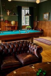 a living room with a pool table and a leather couch at Kalvs Skolhus in Kalv