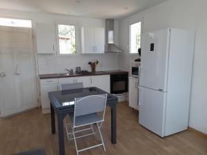 a kitchen with a table and a white refrigerator at CHEZ JACQUES ET MANUE in Six-Fours-les-Plages